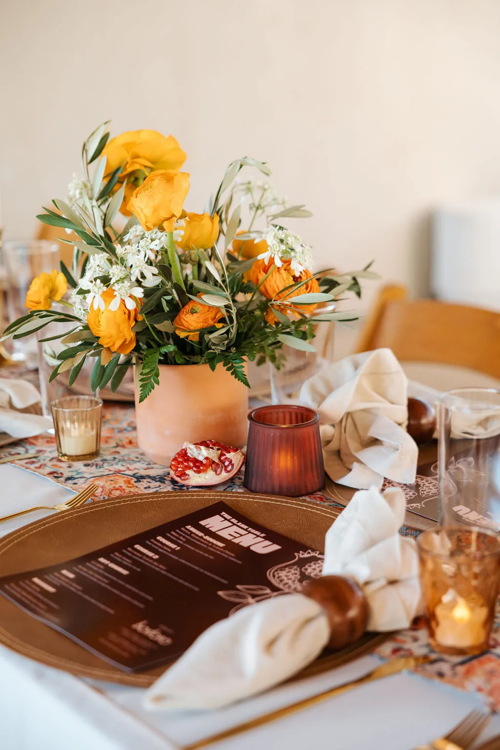 A table setting with a menu card, linen napkin and orange flowers