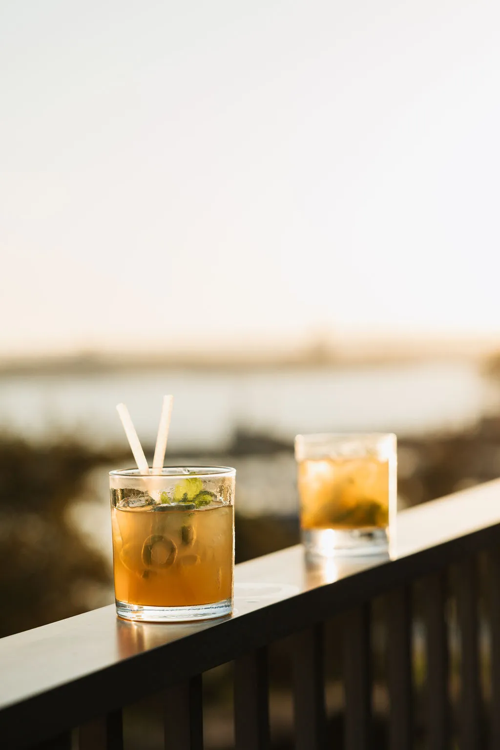 Two cocktails on a ledge overlooking the water at sunset