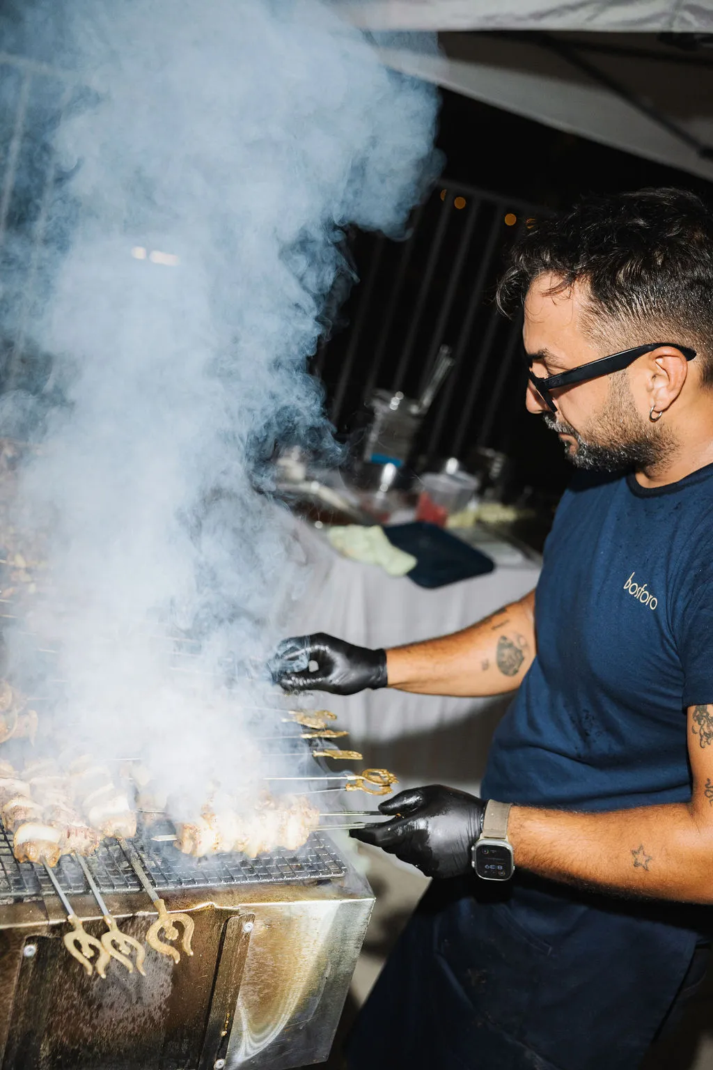 Chef Seckin grilling over open flame with smoke rising