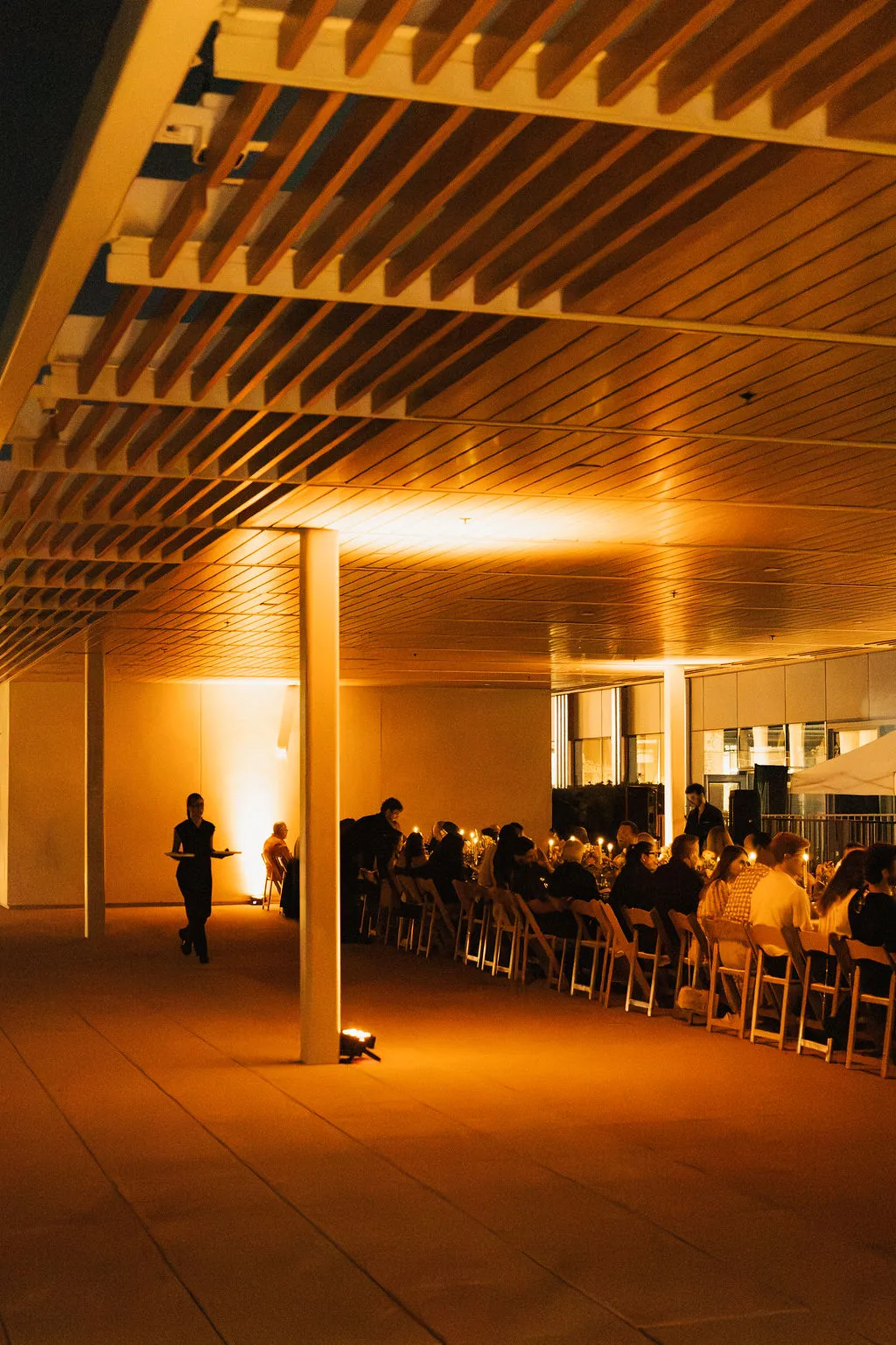 Guests gathered at a long table under warm lights at night