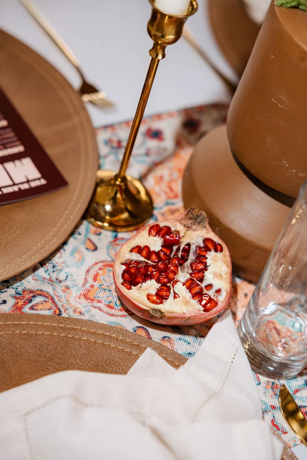 A dinner table with pomegranates, a candle and patterned linen