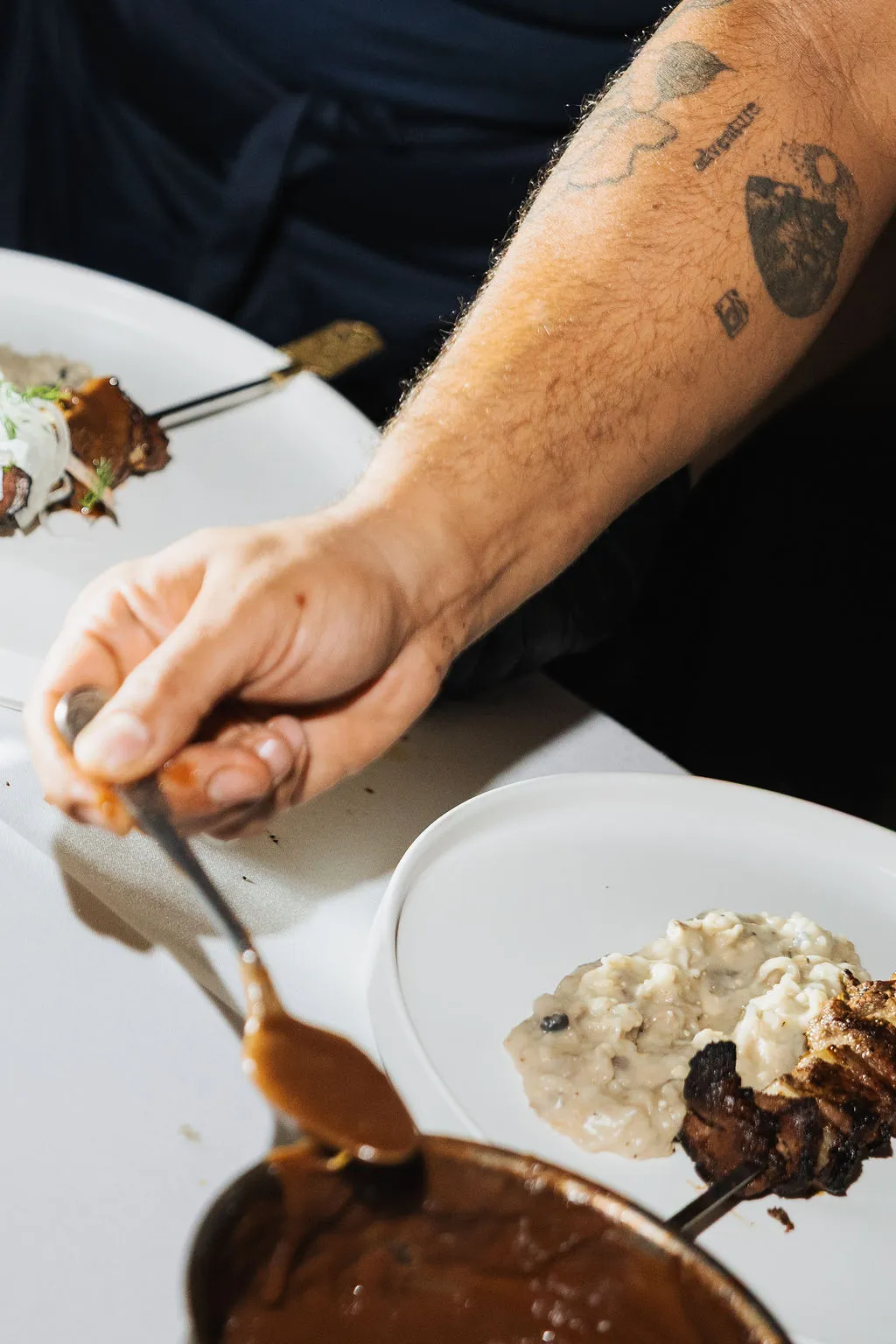 Sauce being spooned over a plated main course